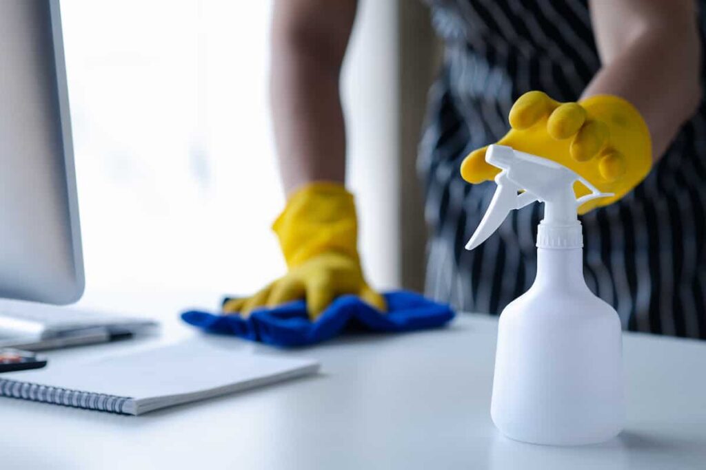 Blue microfiber cloth and spray bottle used by commercial cleaners on a workspace