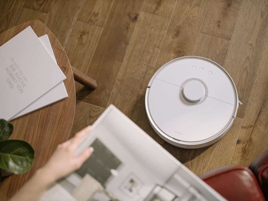 Image of a residential cleaning service worker using smart technologies and robotic cleaners to provide efficient cleaning service